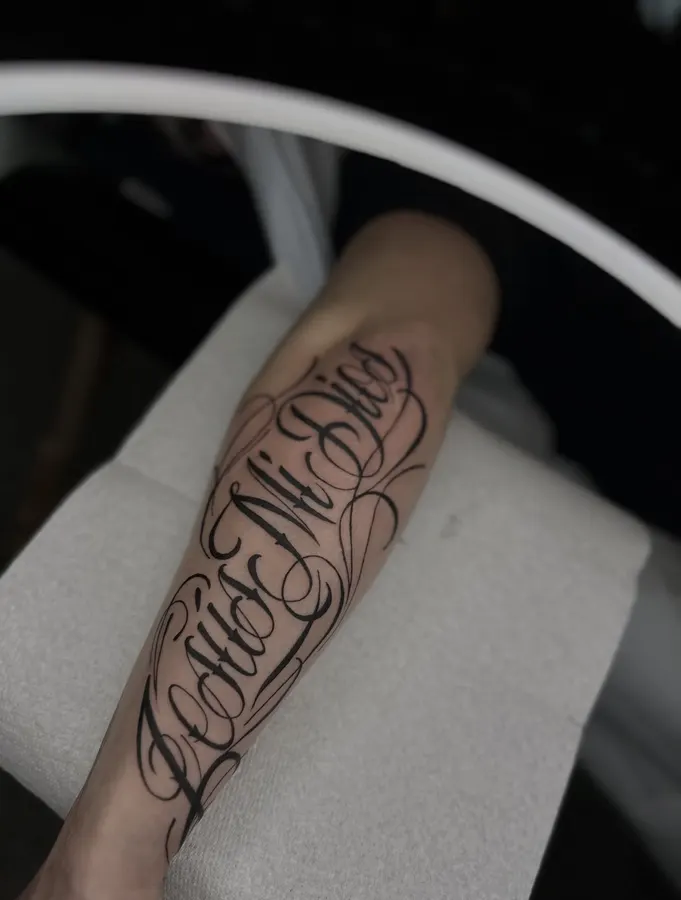 Lettrage fin tatoué sur un avant-bras.